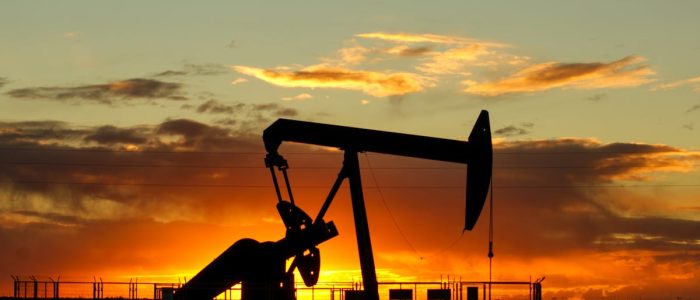 Dramatic silhouette of an oil pump jack against a vibrant sunset sky, emphasizing energy extraction.